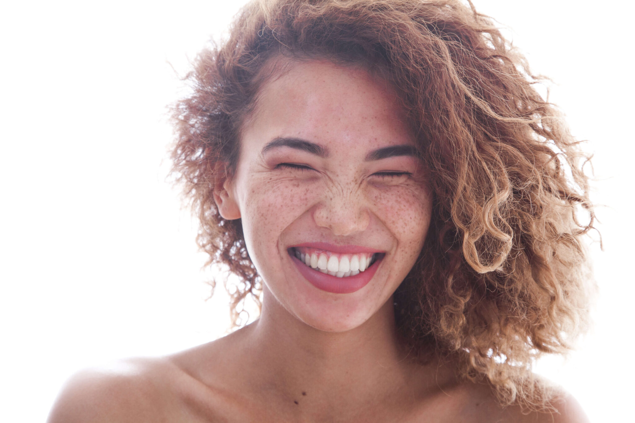 beautiful young woman with curly hair and freckles smiling